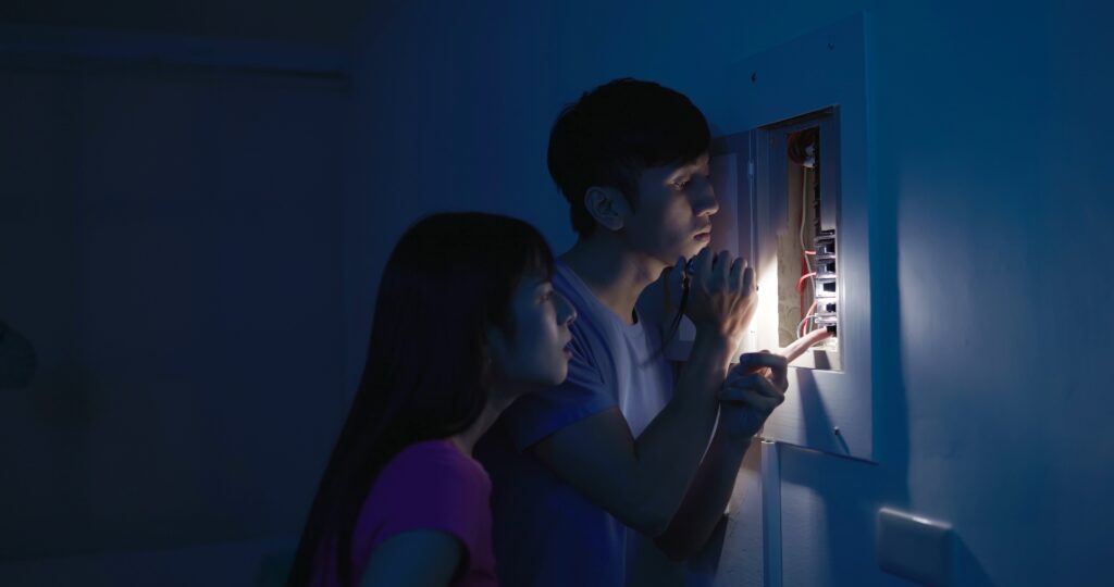 couple looking at circuit breaker to turn power back on after an overload